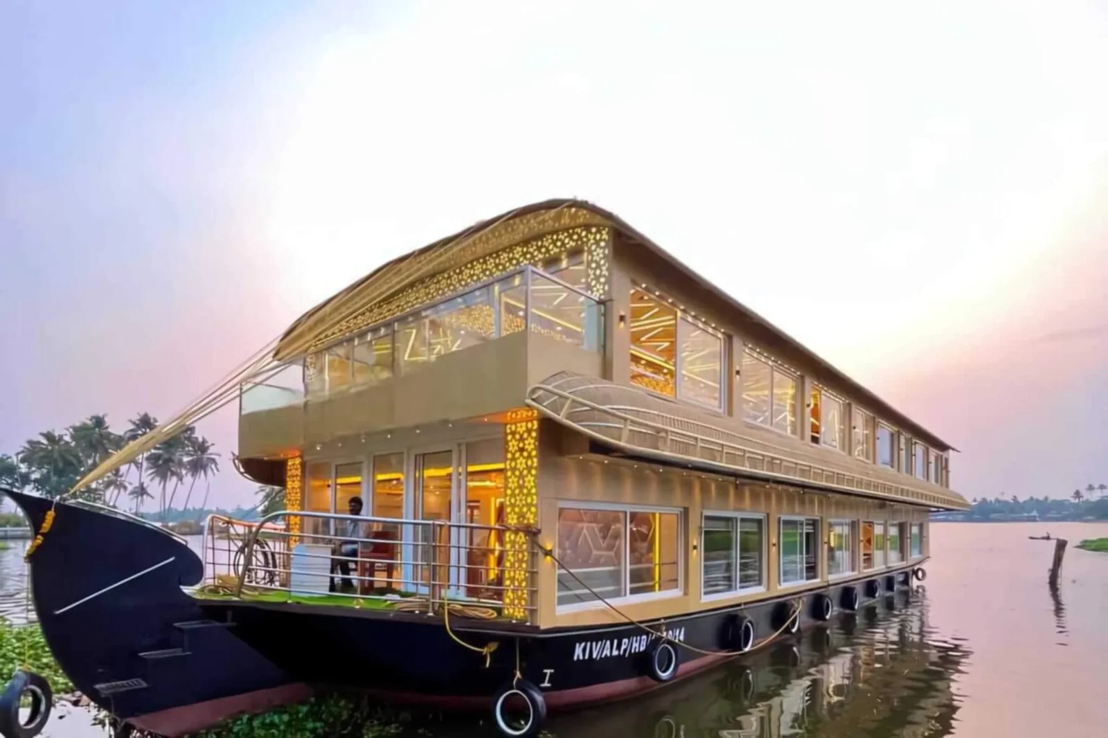 Swarna Thoni ultra luxury 10 bedroom gold glass-walled double-deck houseboat at sunset