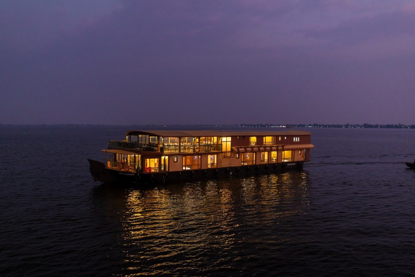 Kumarakom Kottaram luxury 8 bedroom double-deck houseboat glowing on the lake at night