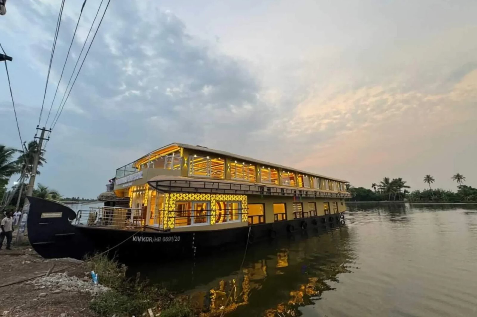 Kayal Kanakam ultra luxury 9 bedroom double-deck houseboat lit up in gold at dusk