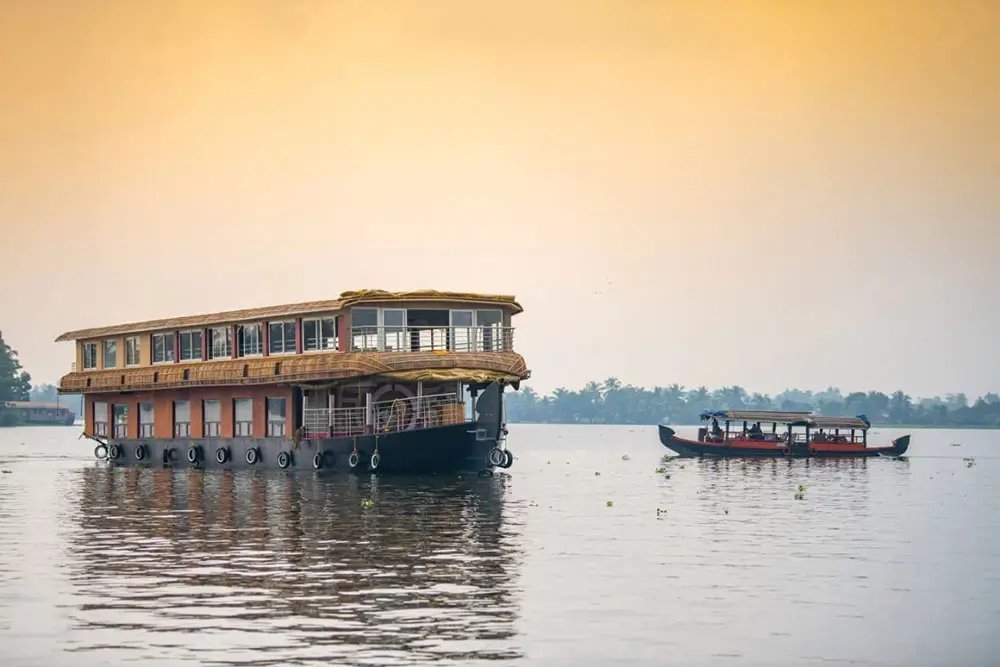 Changanassery Sandhya deluxe 10 bedroom double-deck houseboat on a calm lake at sunset